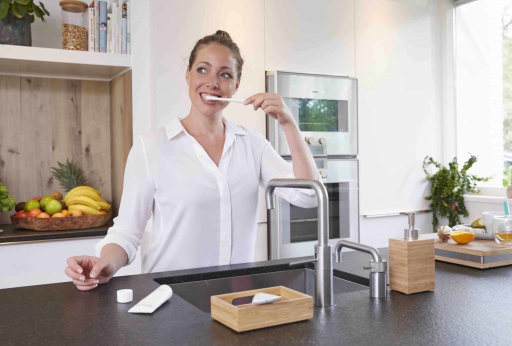 woman brushing teeth in kitchen